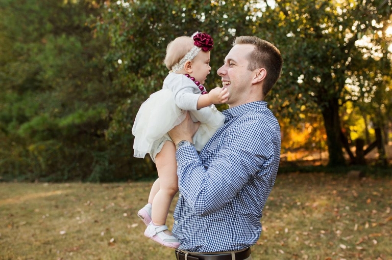 daddy holding his one year old girl up in the air