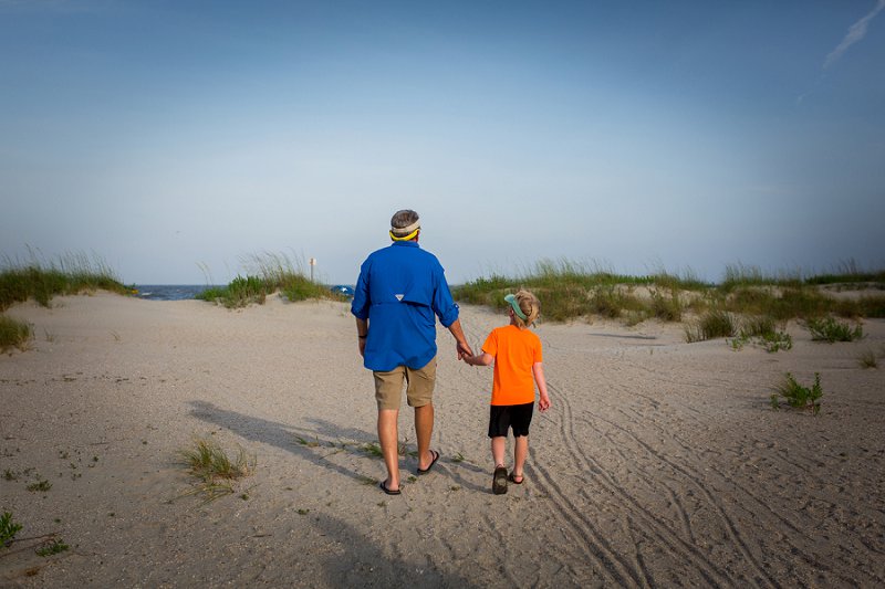 Wild Dunes-Isle of Palms Grandson and grandfather walking hand in hand on the beach