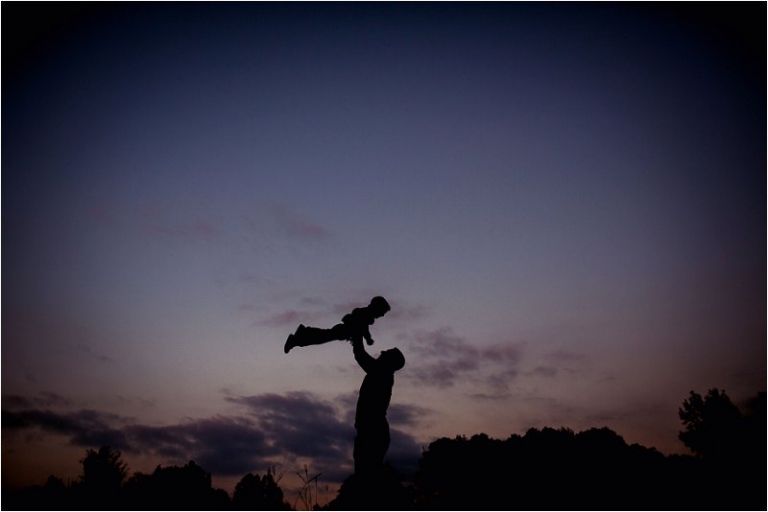 silhouette image of dad holding son in the air