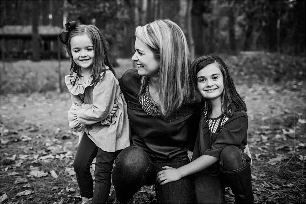 Smiling mother and daughters crouching together for their portrait session