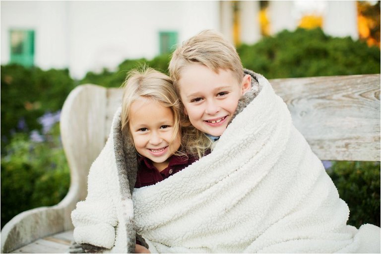 adorable brother and sister snuggling in a blanket
