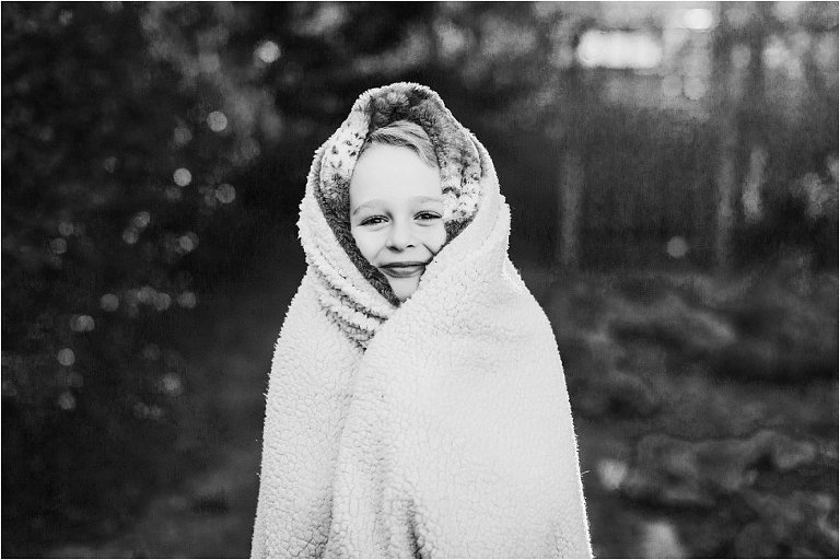 black and white image of little boy snuggled in a blanket
