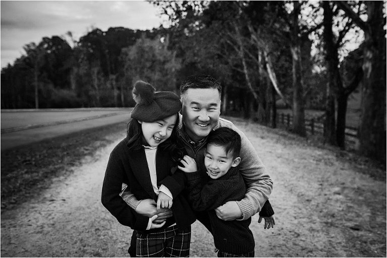 Dad giving big hugs to his adorable little kids. Photo in black and white