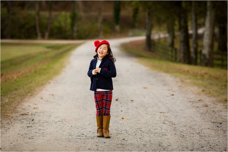 little girl dressed in plaid and navy blue blazer, smiling and posing.