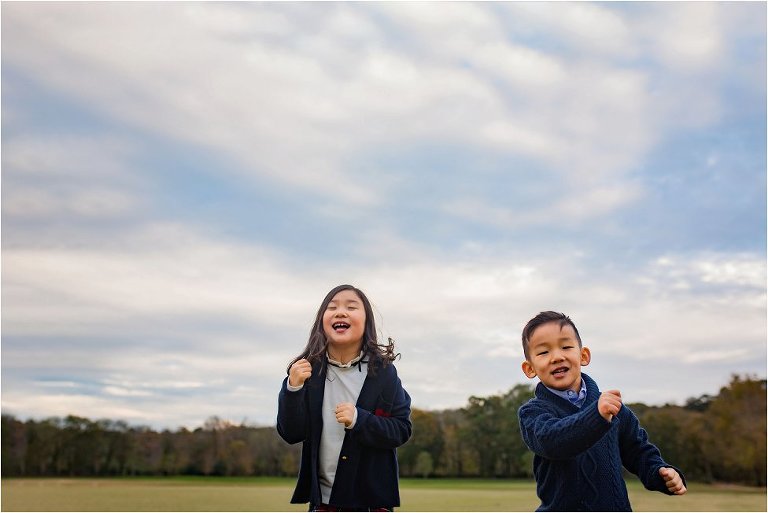 Silly kids running on a polo field, with a big beautiful sky above them.
