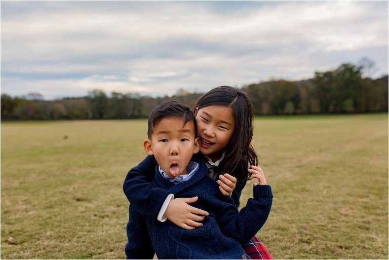 Brother sticking his tongue out while big sister gives him a hug