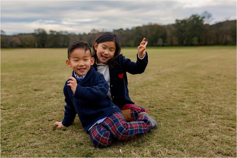 A brother and sister being silly while sitting on the polo fields in Vinings