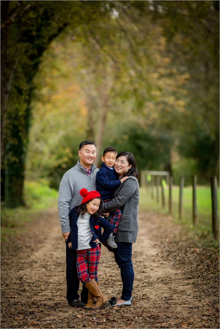Portrait of a beautiful family on a path with warm fall foliage all around them.