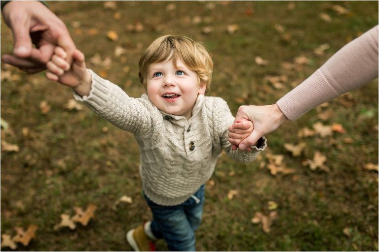 little boy, hand in hand with his parents