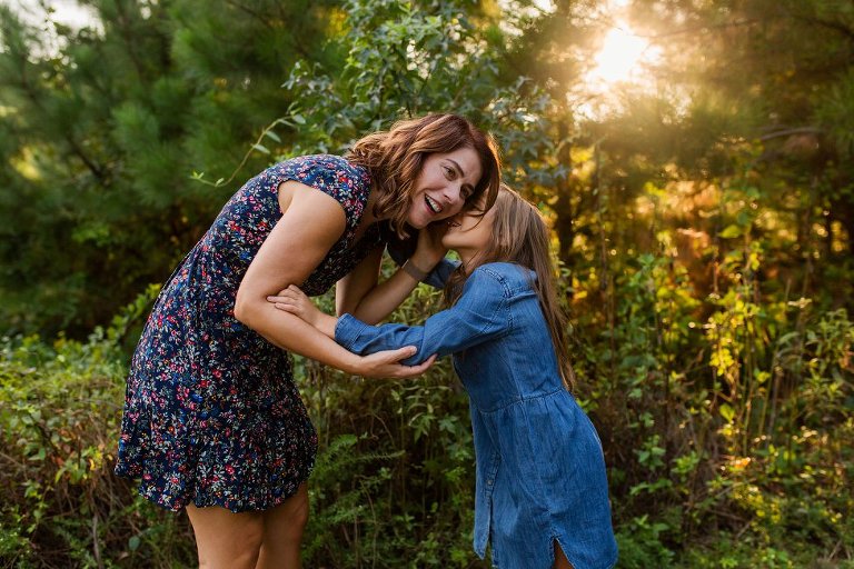 little girl whispering in mom's ear
