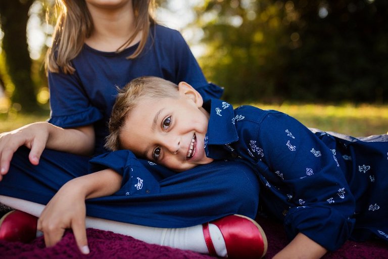 little boy laying on his big sister's leg.