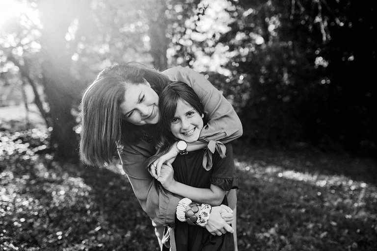 black and white picture of a mom with a huge smile, hugging her daughter closely.