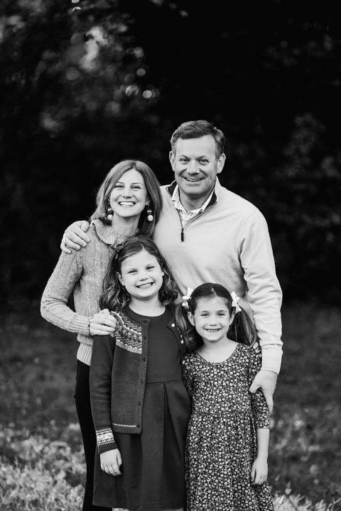 family of four, including 2 little girls, stand and pose for their family picture