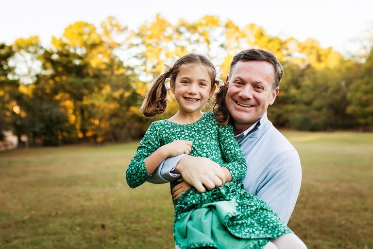 Dad holding up his daughter with cute little pigtails.
