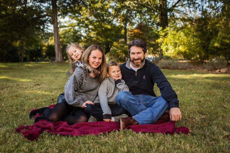 a colorful family photo of four sitting on the side lawn at Barrington Hall in Roswell, Georgia