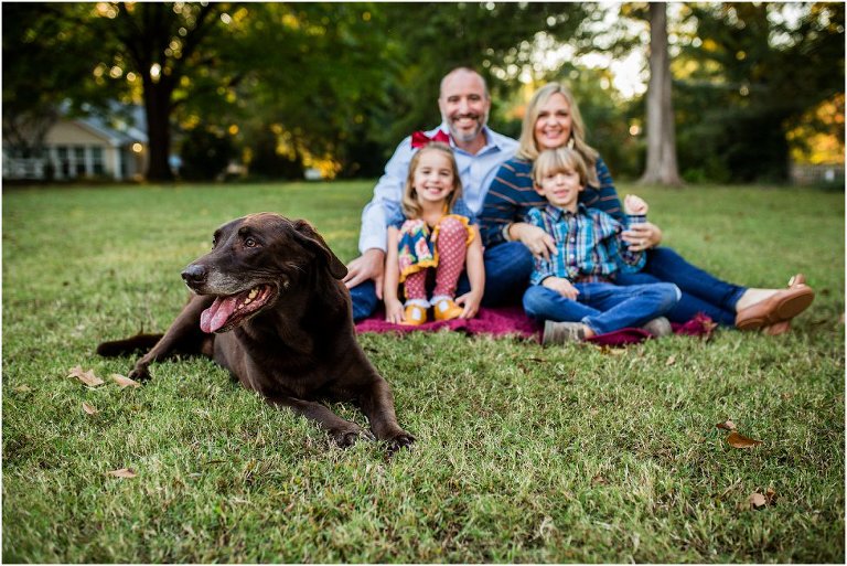 picture of a family of four with their beloved chocolate lab front and center.