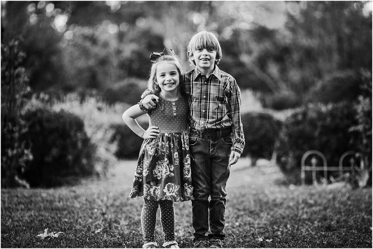 black and white image of a brother and sister posing for their picture