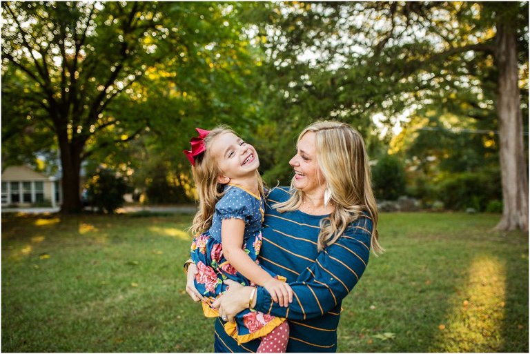 mom holding her daughter and her daughter leaning back and smiling.