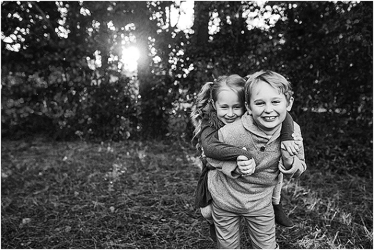 black and white photo of a little boy giving his sister a piggy back ride