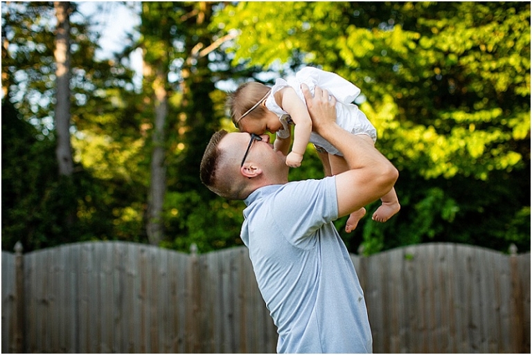 A dad holding his little baby girl in the air, foreheads touching.