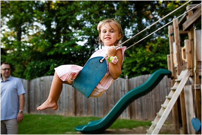 Little girl with a bow in her hair and on her wrist swing on her swingset.