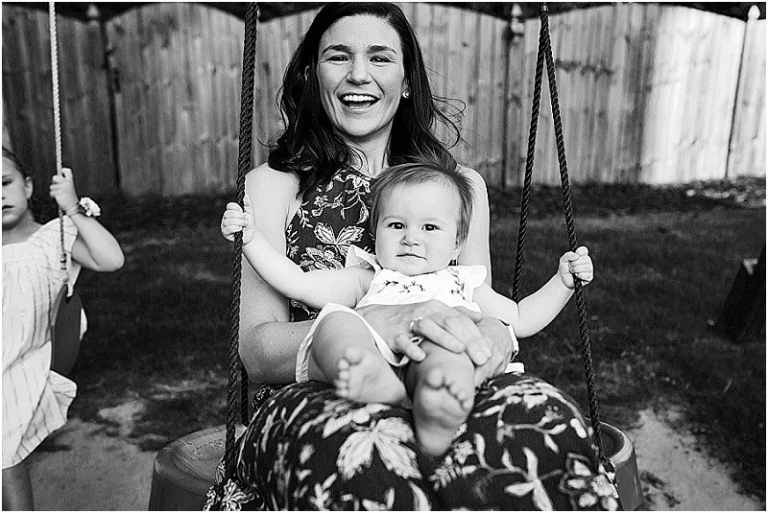 Mom holding baby while swinging on their swingset.