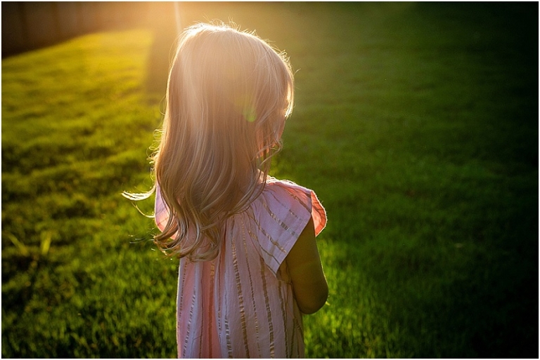 Sun's rays falling on a little girl's hair as she faces in the other direction.