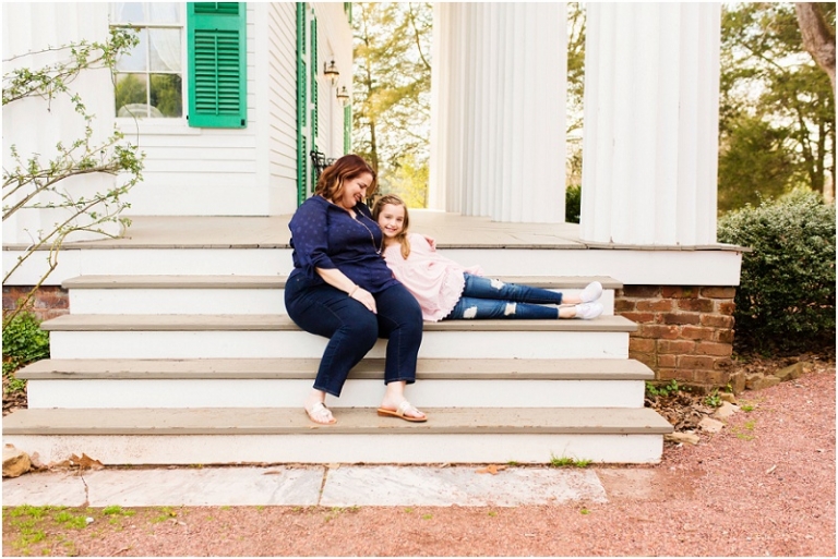 daughter leaning into mom's arms while sitting on the steps of Barrington Hall, Roswell, Georgia.