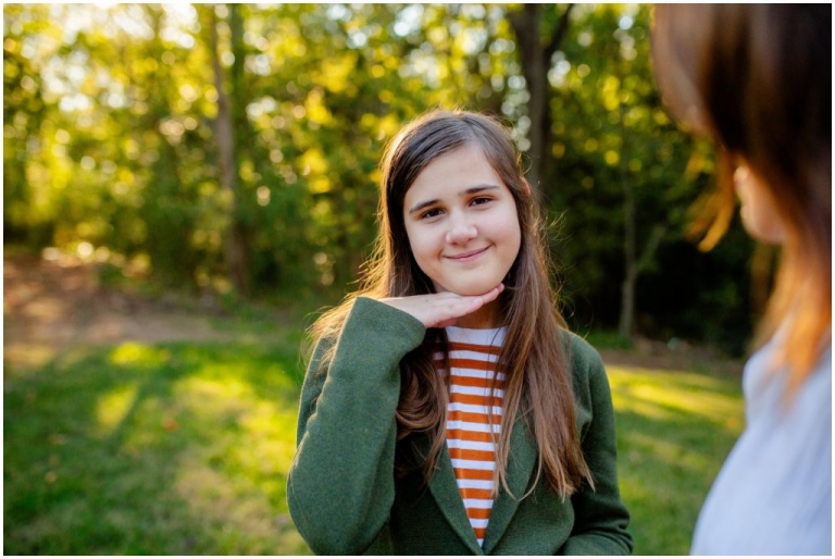 little girl smiling with her hand under her chin