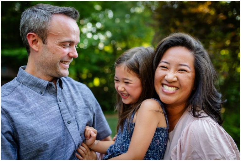 smiling mom hugging her little girl and husband